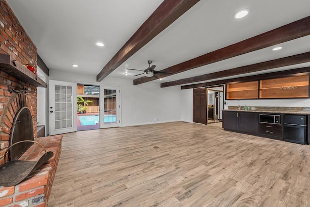 unfurnished living room featuring beamed ceiling, a barn door, light hardwood / wood-style floors, and a fireplace