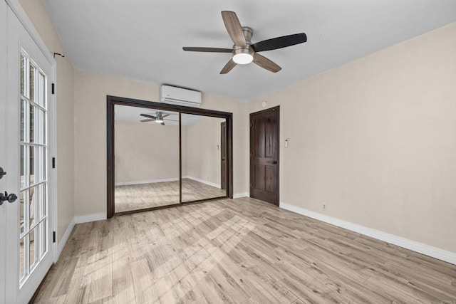 unfurnished bedroom with an AC wall unit, french doors, a closet, ceiling fan, and light hardwood / wood-style flooring