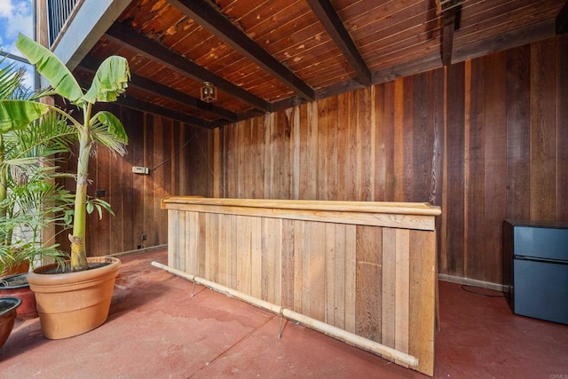 interior space with beamed ceiling, wood walls, and wooden ceiling