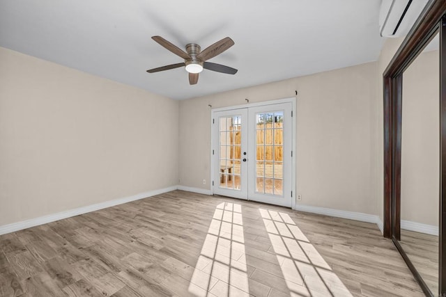 empty room featuring light hardwood / wood-style flooring, an AC wall unit, ceiling fan, and french doors