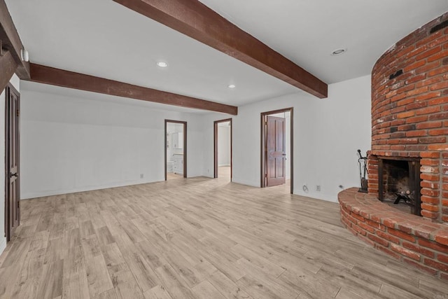 unfurnished living room featuring a fireplace, light wood-type flooring, and beamed ceiling