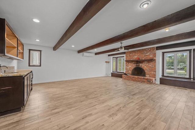 living room featuring a brick fireplace, plenty of natural light, beamed ceiling, and a wall mounted air conditioner