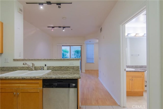 kitchen with dishwasher, sink, rail lighting, light tile patterned flooring, and light stone counters