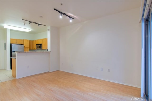 interior space featuring rail lighting and light hardwood / wood-style flooring