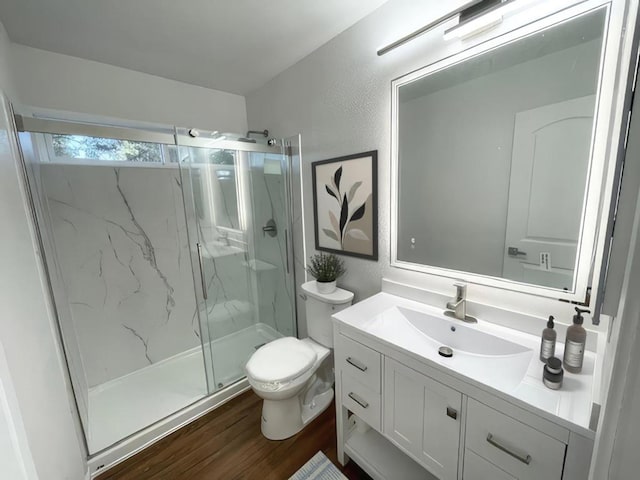 bathroom with hardwood / wood-style flooring, vanity, a shower with shower door, and toilet