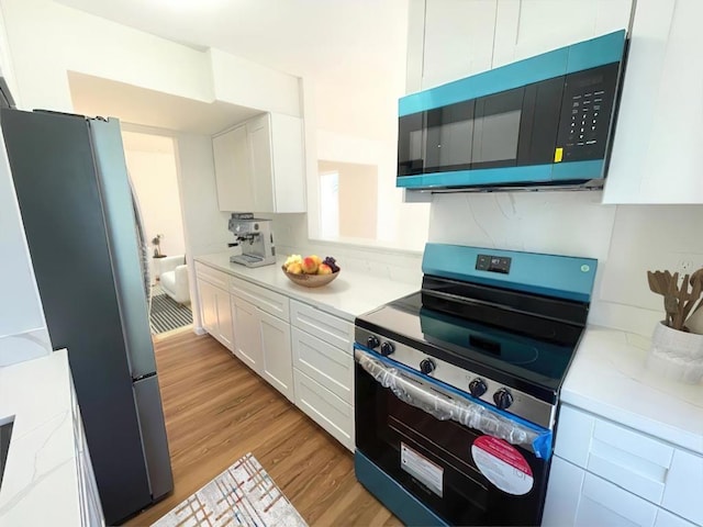 kitchen featuring appliances with stainless steel finishes, light wood-type flooring, and white cabinets