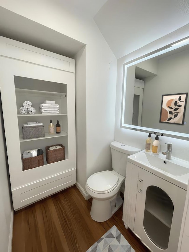 bathroom featuring vanity, wood-type flooring, lofted ceiling, and toilet