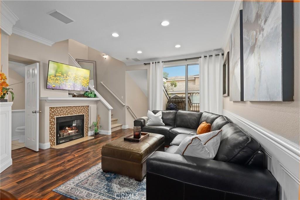 living room featuring crown molding, dark wood-type flooring, and a tiled fireplace