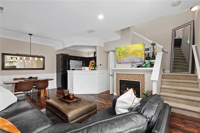 living room featuring crown molding, dark hardwood / wood-style floors, and a tiled fireplace