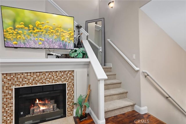 stairway featuring a tiled fireplace and hardwood / wood-style flooring