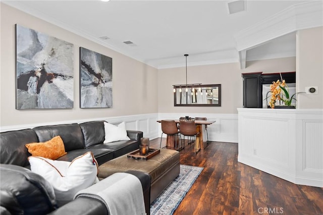 living room with crown molding, dark wood-type flooring, and a notable chandelier