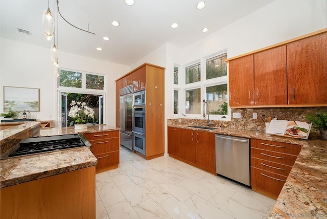 kitchen featuring decorative light fixtures, built in appliances, tasteful backsplash, sink, and light stone counters