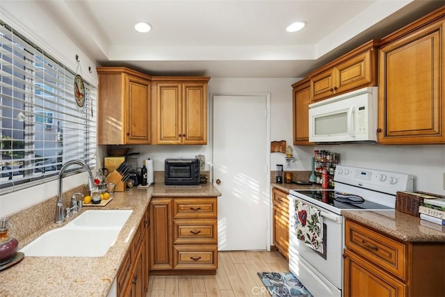 kitchen featuring a tray ceiling, sink, white appliances, and light wood-type flooring