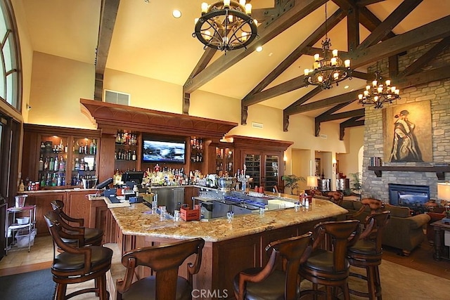 bar featuring an inviting chandelier, light stone countertops, high vaulted ceiling, and dark tile patterned flooring