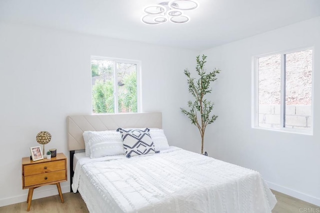 bedroom with light hardwood / wood-style floors and multiple windows