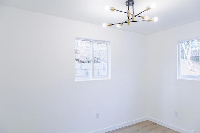 unfurnished room with a chandelier and light hardwood / wood-style flooring