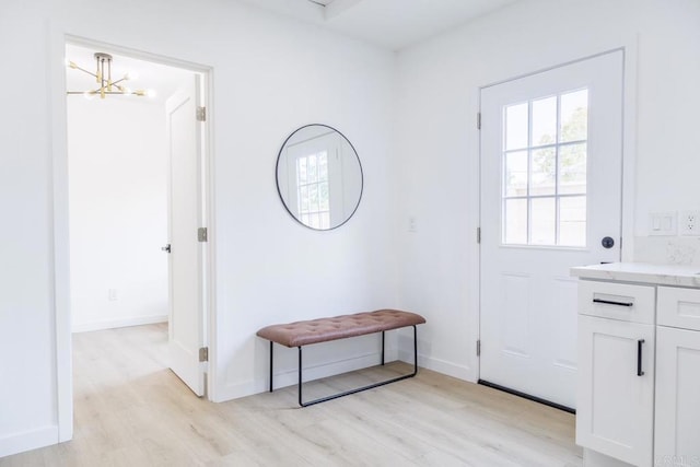 doorway to outside with an inviting chandelier and light hardwood / wood-style flooring