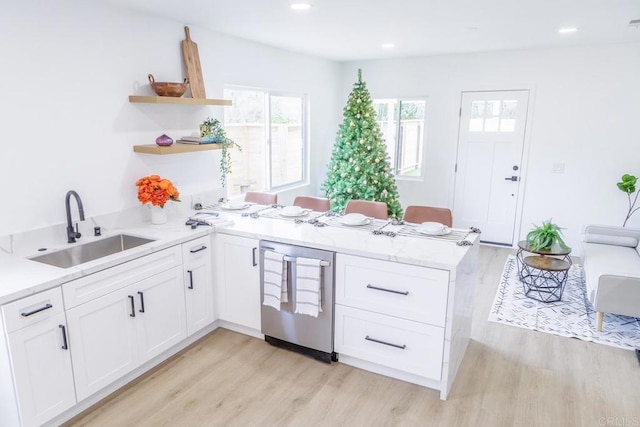 kitchen with kitchen peninsula, light hardwood / wood-style flooring, dishwasher, sink, and white cabinets