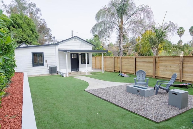 rear view of house featuring a patio, a yard, central AC unit, and an outdoor fire pit