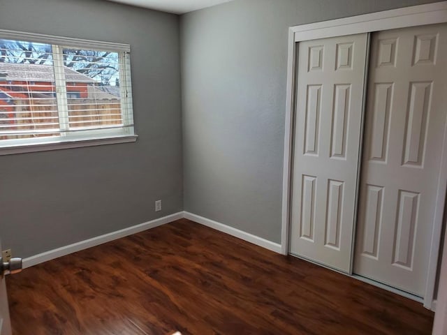 unfurnished bedroom with dark hardwood / wood-style floors and a closet