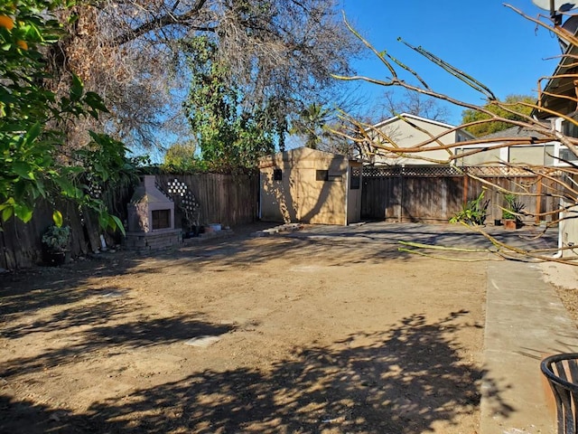 view of yard featuring a patio, exterior fireplace, and a storage shed