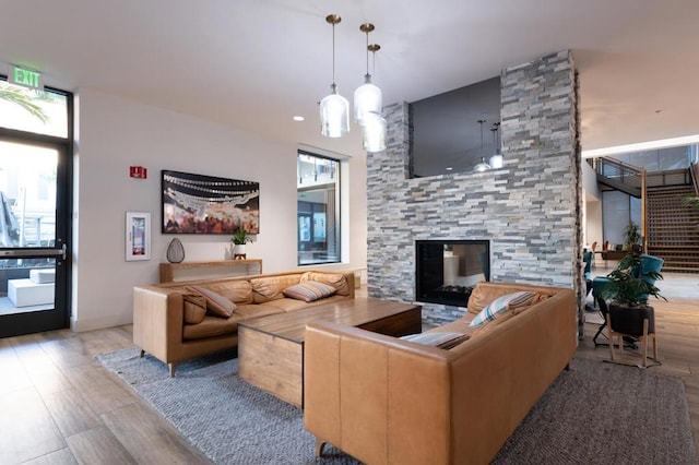 living room with a stone fireplace and light wood-type flooring