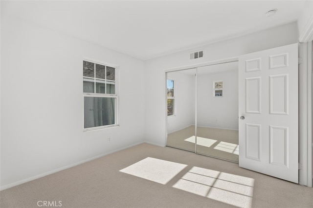 unfurnished bedroom featuring light carpet and a closet