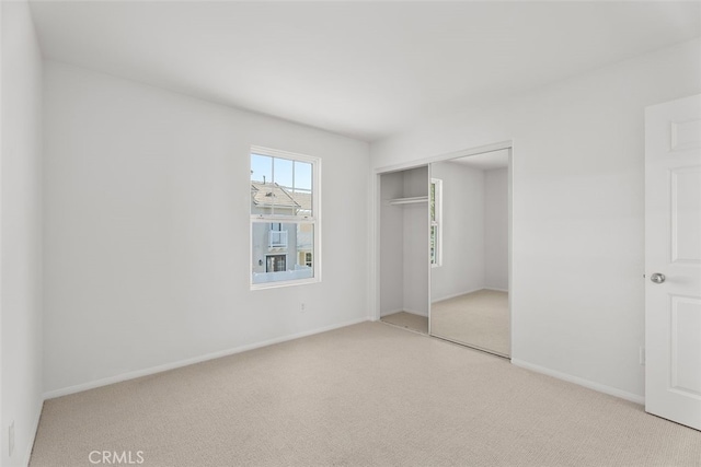 unfurnished bedroom with light colored carpet and a closet