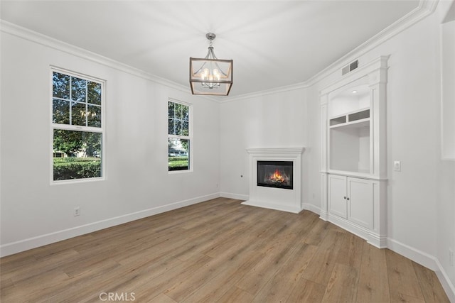 unfurnished living room with crown molding, light wood-type flooring, and a chandelier