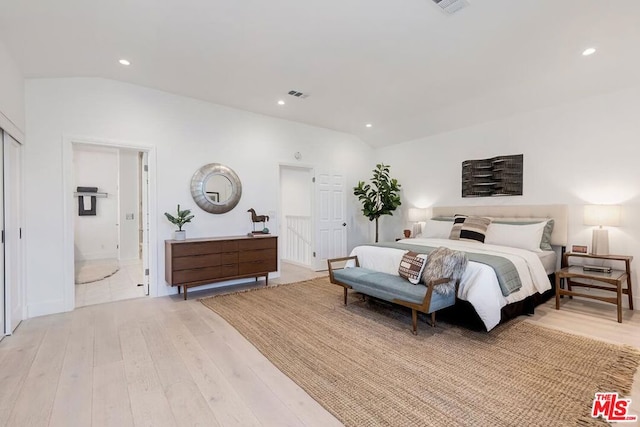 bedroom featuring lofted ceiling, connected bathroom, and light hardwood / wood-style floors