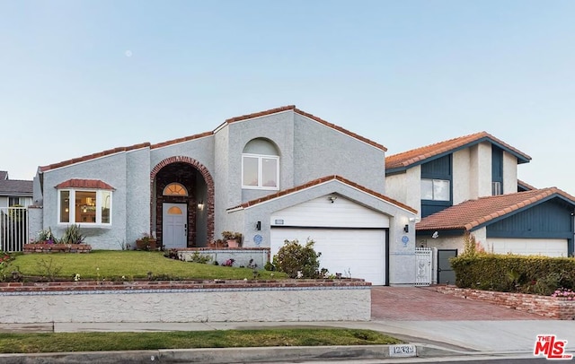 mediterranean / spanish-style home featuring a garage and a front lawn