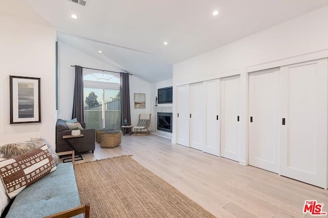 living room featuring lofted ceiling and light hardwood / wood-style flooring