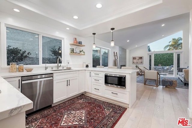 kitchen featuring appliances with stainless steel finishes, pendant lighting, white cabinetry, sink, and light hardwood / wood-style flooring