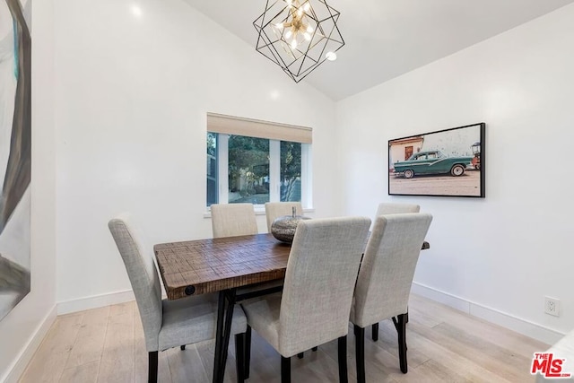 dining area with high vaulted ceiling, a chandelier, and light hardwood / wood-style flooring