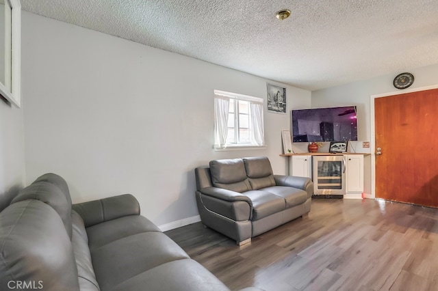 living room featuring wood-type flooring, a textured ceiling, and wine cooler