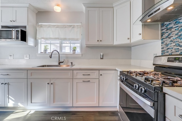 kitchen featuring sink, white cabinetry, appliances with stainless steel finishes, and range hood