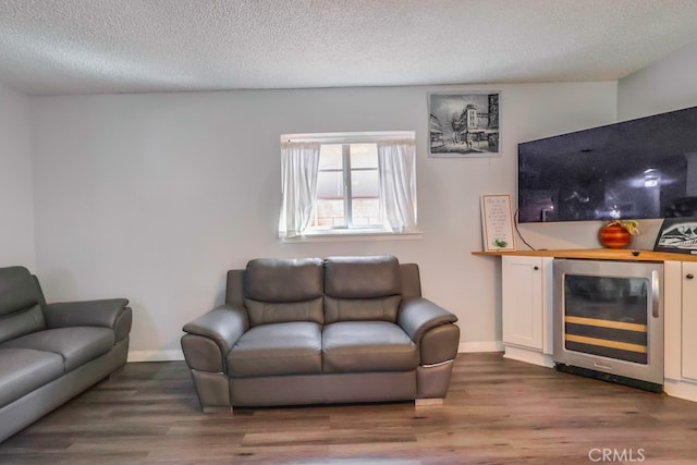 living room with a textured ceiling, beverage cooler, and hardwood / wood-style floors