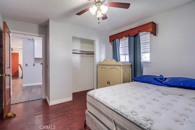 bedroom with a closet, a textured ceiling, dark hardwood / wood-style floors, and ceiling fan