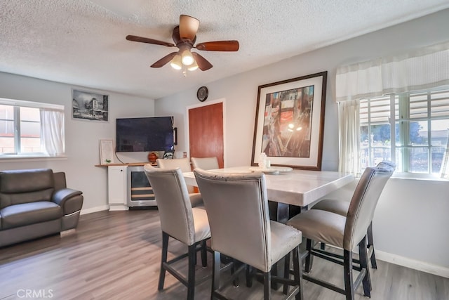 dining space featuring hardwood / wood-style floors, a textured ceiling, beverage cooler, and ceiling fan