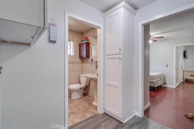 bathroom featuring hardwood / wood-style flooring, ceiling fan, a textured ceiling, and toilet