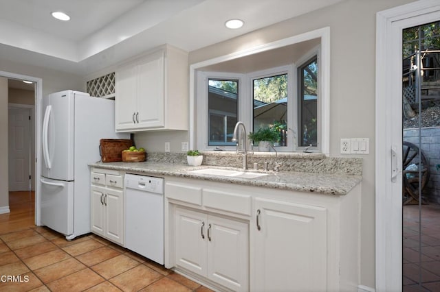 kitchen with white appliances, white cabinets, sink, light stone counters, and light tile patterned floors