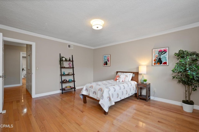 bedroom featuring light hardwood / wood-style floors, a textured ceiling, and crown molding