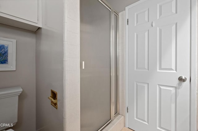 bathroom featuring toilet and a shower with door