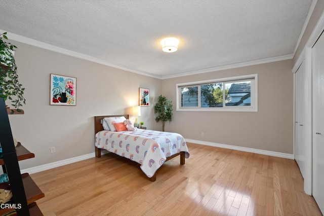 bedroom featuring a textured ceiling, crown molding, and light wood-type flooring