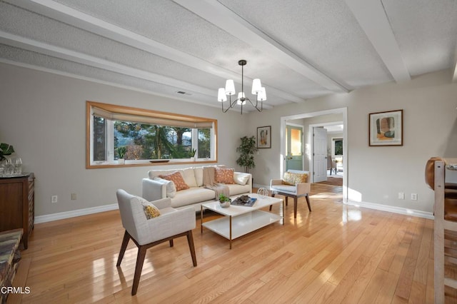 living room with a textured ceiling, light hardwood / wood-style flooring, beamed ceiling, and an inviting chandelier