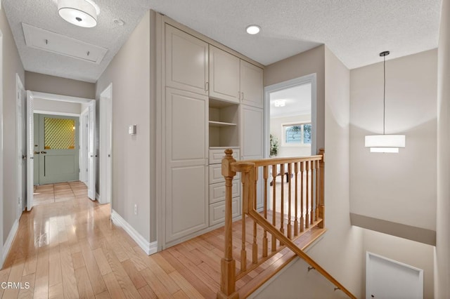 corridor featuring a textured ceiling and light hardwood / wood-style flooring