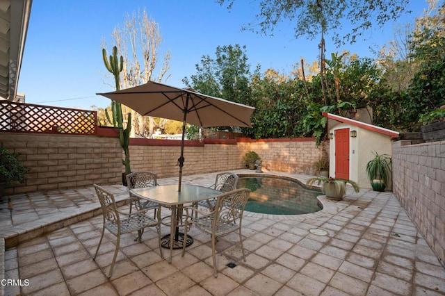 view of patio / terrace featuring a fenced in pool and a shed