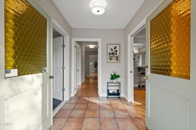 hall featuring a textured ceiling and light tile patterned flooring