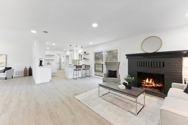 living room featuring a brick fireplace and light hardwood / wood-style floors