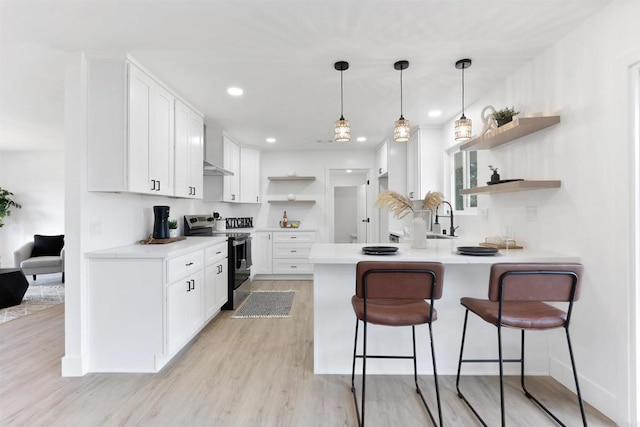 kitchen with a breakfast bar, decorative light fixtures, stainless steel electric range, kitchen peninsula, and white cabinets